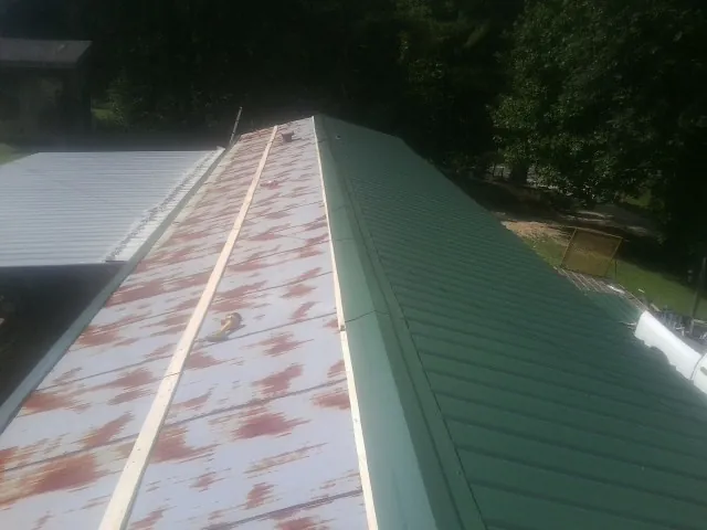 Old rusted panels beside newly installed green metal roofing — Wind Damage Roof Repair by Roofing Brothers in Cedar Knolls