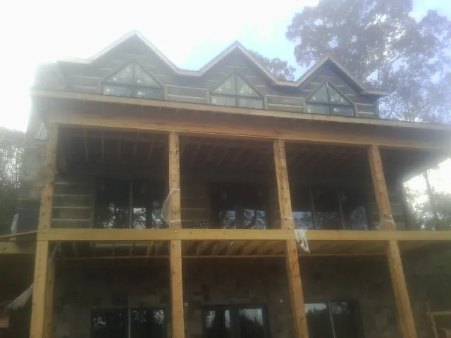 Dormers and porch framing on a large log home under construction — Roof Coating work by our crew in Cedar Knolls