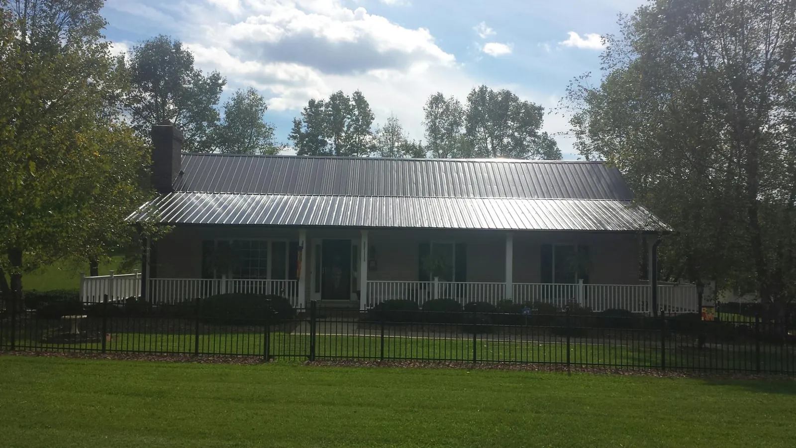 Gray metal roof on a brick ranch with a full width front porch — Gutter Guard Installation work by our crew in Cedar Knolls