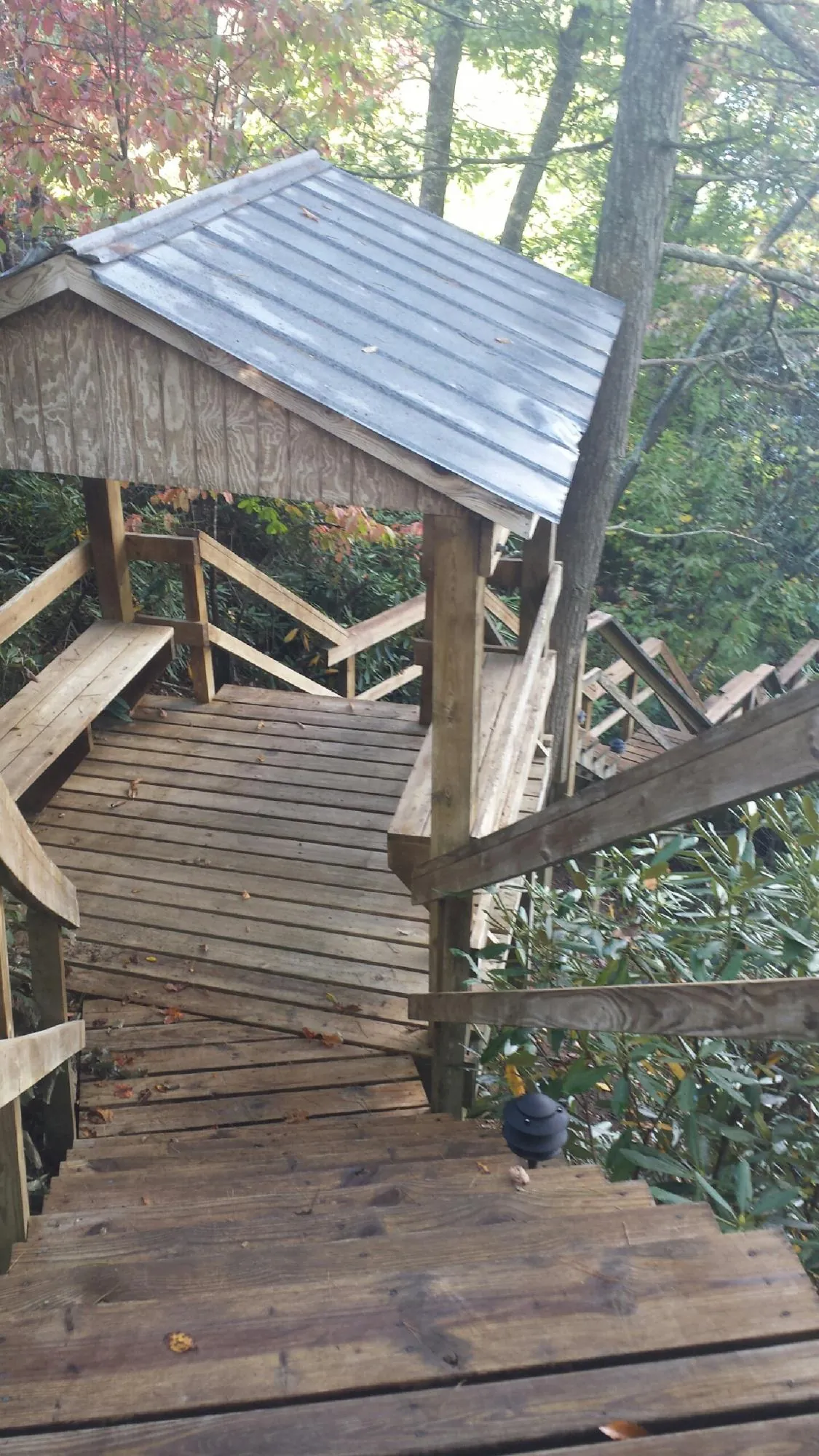 Metal roofed shelter over wooden steps on a wooded walkway — Skylight Repair & Installation work by our crew in Cedar Knolls
