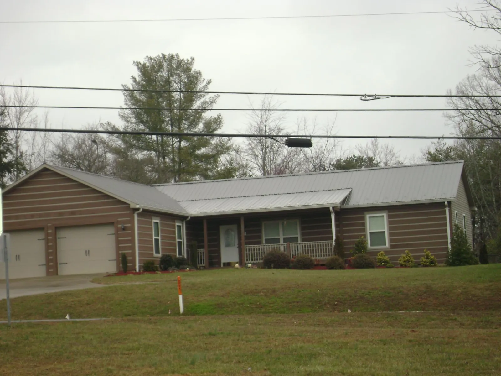 Gray metal roof on a log sided ranch home with a front porch in Cedar Knolls
