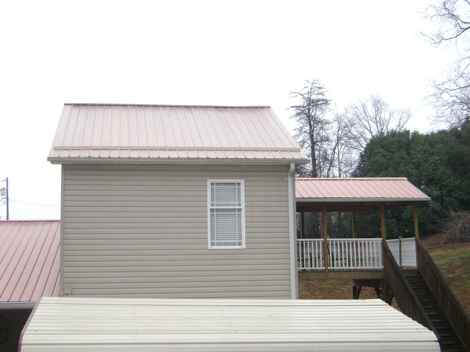Tan metal roofs on a two story addition and attached porch, from a Roof Replacement job in Cedar Knolls