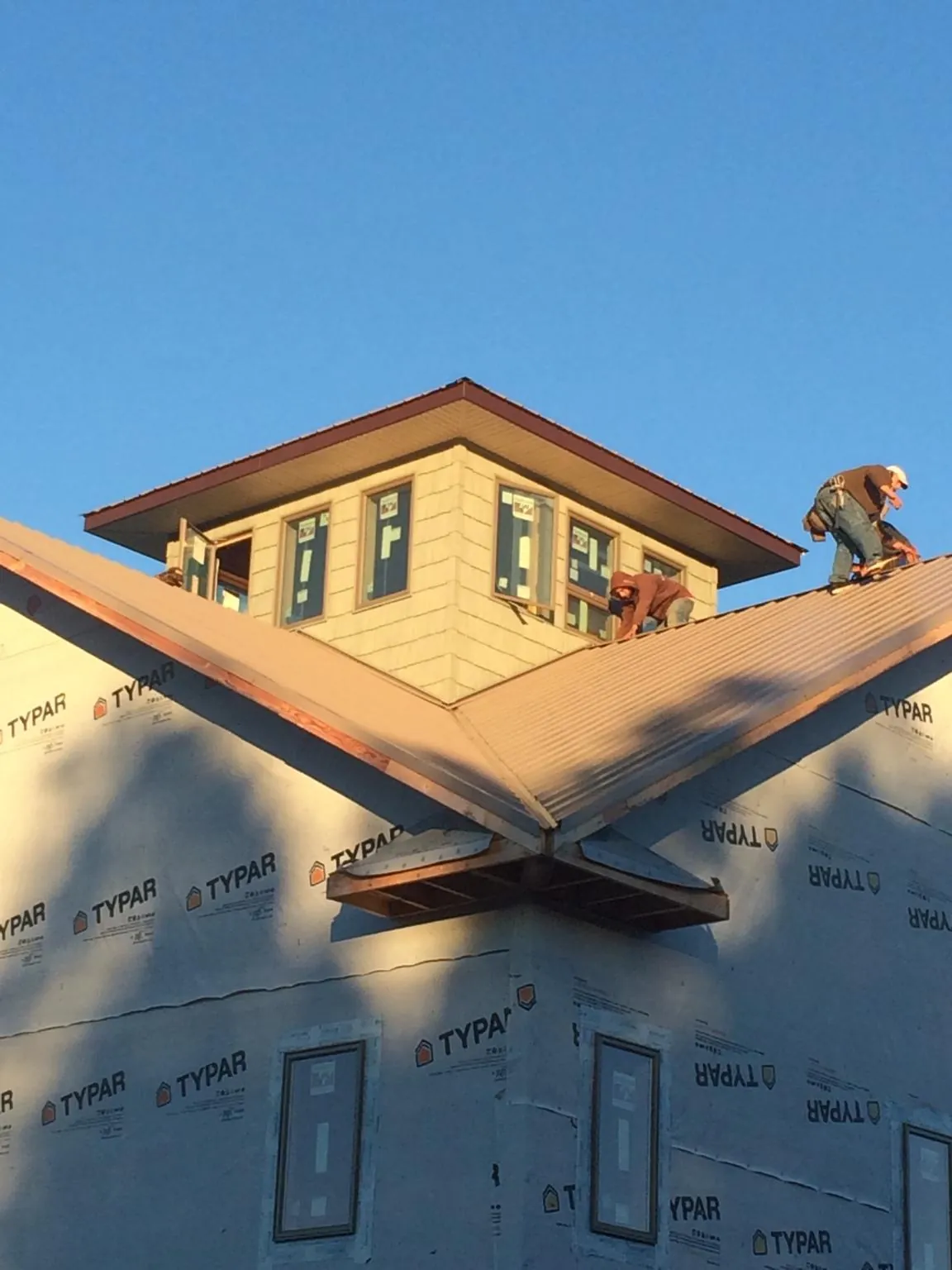 Roofers working around a rooftop cupola on a new metal roof at sunset — Roof Waterproofing in Cedar Knolls by Roofing Brothers